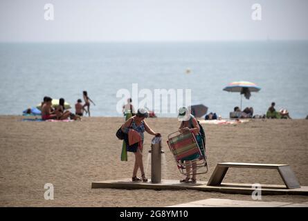 Malaga, Spanien. Juli 2021. Am Strand von Malagueta werden Frauen während eines heißen Sommertages inmitten einer Coronavirus-Pandemie beobachtet, wie sie ihre Beine abkühlen.die staatliche Wetteragentur AEMET sagte, dass die Temperaturen am nächsten Tag in Andalusien mit mehr als 40º Grad in Malaga und anderen Provinzen steigen werden. Viele Badegäste werden erwartet, an den Stränden anzukommen, um sich zu sonnen und die sonnigen Tage zu genießen. Kredit: SOPA Images Limited/Alamy Live Nachrichten Stockfoto