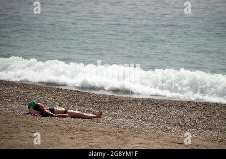 Malaga, Spanien. Juli 2021. Während eines heißen Sommertages inmitten einer Coronavirus-Pandemie wird eine Frau am Strand von Malagueta beim Sonnenbaden beobachtet.die staatliche Wetteragentur AEMET sagte, dass die Temperaturen am nächsten Tag in Andalusien mit mehr als 40º Grad in Malaga und anderen Provinzen steigen werden. Viele Badegäste werden erwartet, an den Stränden anzukommen, um sich zu sonnen und die sonnigen Tage zu genießen. Kredit: SOPA Images Limited/Alamy Live Nachrichten Stockfoto