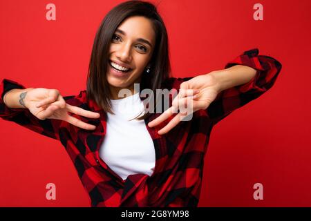 Nahaufnahme von jungen glücklich positive lächelnd cool schönen Brunet weibliche Person mit aufrichtigen Emotionen tragen weißes T-Shirt und stilvollen roten Karo-Shirt Stockfoto