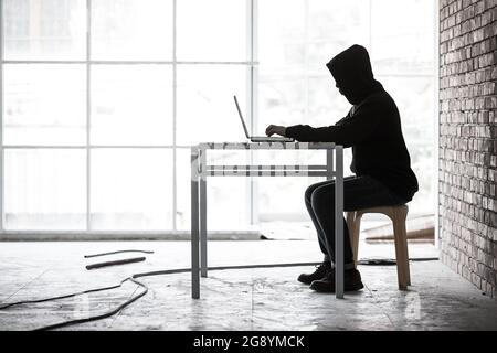 Hacker arbeiten an einem versteckten Ort und nutzen Labtop, Konzept für Computerkriminalität und illegale Aktionen im Internet Stockfoto