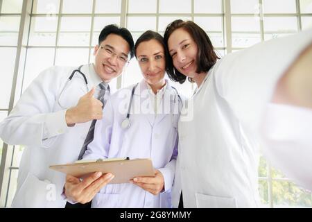 Eine Gruppe von drei Diversity-Personen, Arzt und Assistentin, macht zusammen mit Glück und lächelnden Gesichtern ein Selfie-Foto. Konzept für erfolgreiches Team. Stockfoto