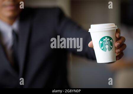 BANGKOK, THAILAND - JULI, 2 2017 : Geschäftsmann in Anzug hält Starbuck Kaffeetasse in der Hand, Starbuck in der beliebtesten Premium-Kaffee in Thailand Stockfoto