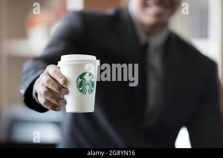 BANGKOK, THAILAND - JULI, 2 2017 : Geschäftsmann in Anzug hält Starbuck Kaffeetasse in der Hand, Starbuck in der beliebtesten Premium-Kaffee in Thailand Stockfoto