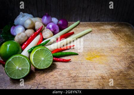 Stillleben Kaffir Limettenblatt, Zitrone, Zitronengras, Galgant, Chili, Zwiebeln und Strohpilze Kräuter und würzige Zutaten Thai-Essen (tom Yum) über Hacken Stockfoto