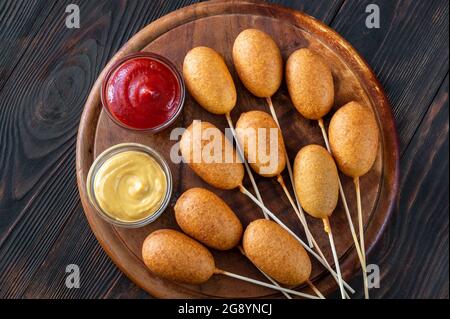 Maishunde mit verschiedenen Dip-Saucen auf Holzbrett Stockfoto