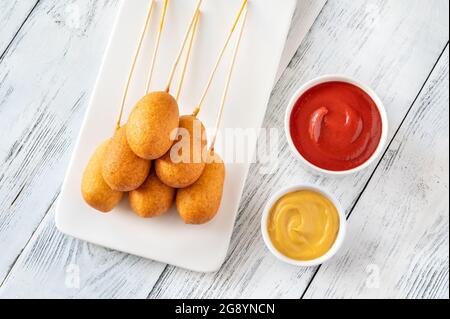 Maishunde mit Dip-Saucen auf weißem Servierteller Stockfoto