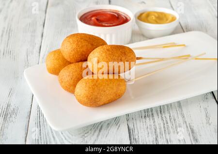 Maishunde mit Dip-Saucen auf weißem Servierteller Stockfoto