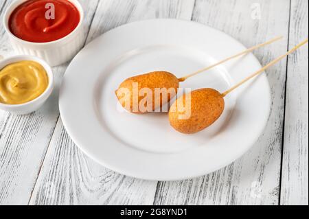 Maishunde mit Dip-Saucen auf weißem Servierteller Stockfoto