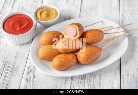 Maishunde mit Dip-Saucen auf weißem Servierteller Stockfoto