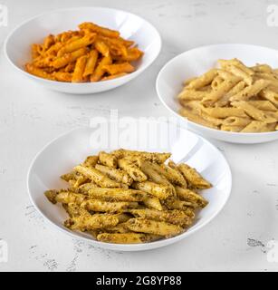 Portionen Penne-Pasta mit traditioneller, orangefarbener und gelber Pesto-Sauce Stockfoto