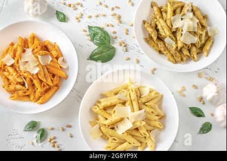 Portionen Penne-Pasta mit traditioneller, orangefarbener und gelber Pesto-Sauce Stockfoto