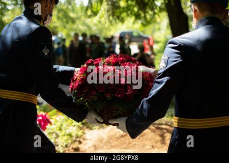 Blumen legen. Das Militär hat Blumen auf das Grab gelegt. Trauerfeier am Kriegsschauort. Stockfoto