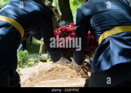 Blumen legen. Das Militär hat Blumen auf das Grab gelegt. Trauerfeier am Kriegsschauort. Stockfoto