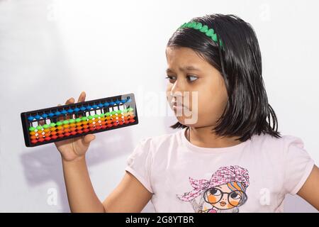 abacus in der Hand gehalten von einem verwirrten indischen Mädchen Kind auf weißem Hintergrund Stockfoto
