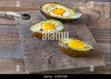 Gebackene Eier in Avocado auf dem Holzbrett Stockfoto