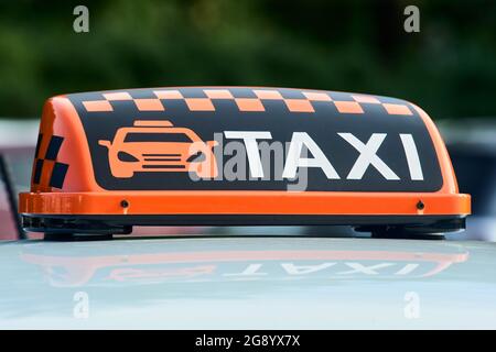 Auf dem Dach des Autos steht ein orangefarbenes Taxistand Stockfoto