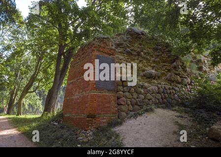GDOV, RUSSLAND - 19. JULI 2020: Ruinen einer Verteidigungsmauer mit einer Gedenktafel an einem sonnigen Julitag. Festung Gdov Stockfoto