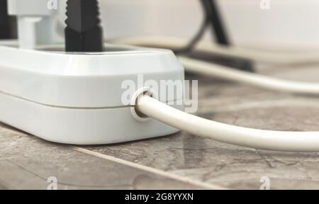 Elektrische Verlängerungsleiste mit angeschlossenen Netzsteckern, Nahaufnahme des elektrischen Verlängerungskabels Stockfoto