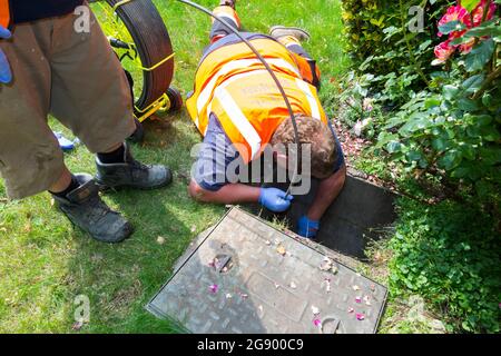 Fremdfirmen, die mit einer Kamera und einer Rolle Glasfaserkabel arbeiten, untersuchen ein verstopftes Kanalablasssystem auf Verstopfung und die Ursache des Problems. VEREINIGTES KÖNIGREICH. (127) Stockfoto