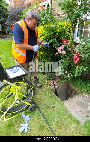 Fremdfirmen, die mit einer Kamera und einer Rolle Glasfaserkabel arbeiten, untersuchen ein verstopftes Kanalablasssystem auf Verstopfung und die Ursache des Problems. VEREINIGTES KÖNIGREICH. (127) Stockfoto