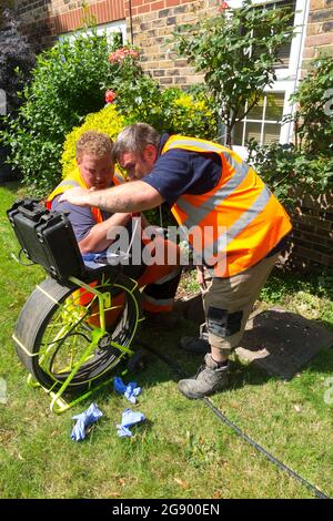 Fremdfirmen, die mit einer Kamera und einer Rolle Glasfaserkabel arbeiten, untersuchen ein verstopftes Kanalablasssystem auf Verstopfung und die Ursache des Problems. VEREINIGTES KÖNIGREICH. (127) Stockfoto