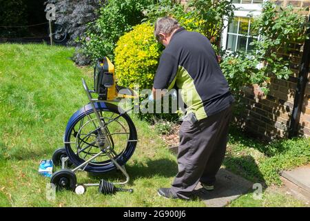 Fremdfirmen, die mit einer Kamera und einer Rolle Glasfaserkabel arbeiten, untersuchen ein verstopftes Kanalablasssystem auf Verstopfung und die Ursache des Problems. VEREINIGTES KÖNIGREICH. (127) Stockfoto