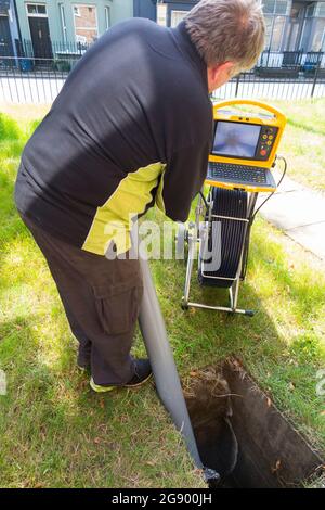 Fremdfirmen, die mit einer Kamera und einer Rolle Glasfaserkabel arbeiten, untersuchen ein verstopftes Kanalablasssystem auf Verstopfung und die Ursache des Problems. VEREINIGTES KÖNIGREICH. (127) Stockfoto