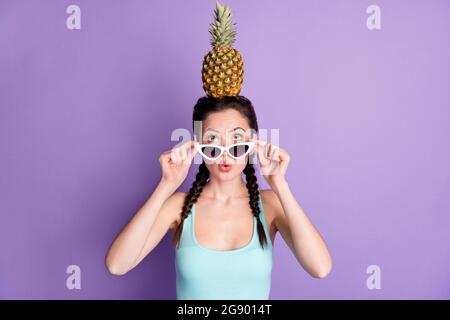 Portrait von attraktiven Comic lustig erstaunt Mädchen hält auf dem Kopf Ananas Pout Lippen isoliert über violett lila Farbe Hintergrund Stockfoto