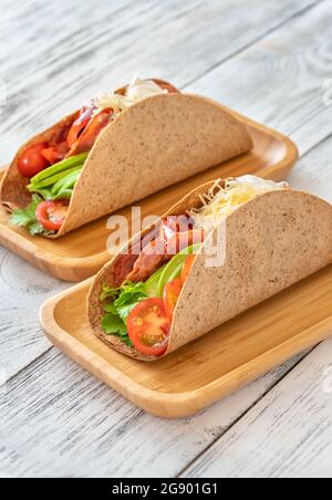 Tacos mit Schinken und Gemüse auf dem servierten Holzteller Stockfoto