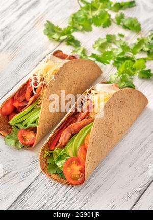 Tacos mit Schinken und Gemüse auf dem servierten Holzteller Stockfoto