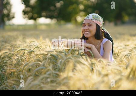 Lächelnde junge Frau, die mit geschlossenen Augen im Weizenfeld steht und genießt Stockfoto