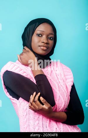 Junge Frau in Hijab und Sweatshirt Weste auf blauem Hintergrund Stockfoto