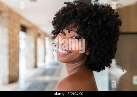 Lächelnde Afro-Frau, die über die Schulter schaut Stockfoto