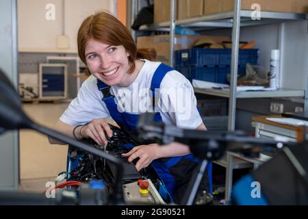 Lächelnde Technikerin schaut weg, während sie in der Werkstatt arbeitet Stockfoto