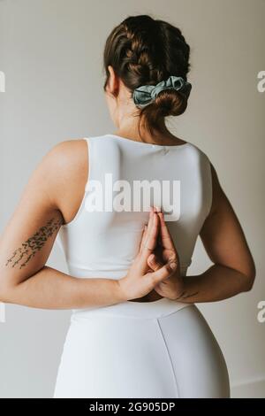 Weibliche Fitness-Ausbilderin mit den Händen hinter dem Rücken geklammert und Yoga im Health Club Stockfoto