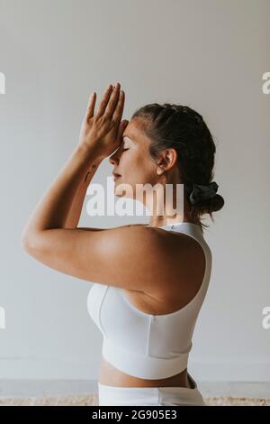 Fitnesstrainer mit zusammengeklemmten Händen und Yoga-Übungen im Fitnessclub Stockfoto