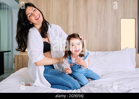 Glückliche, schwanger Mutter, die zu Hause mit ihrer Tochter auf dem Bett spielt Stockfoto