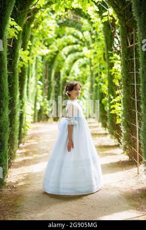 Lächelndes nettes Mädchen im weißen Abendkleid im Garten Stockfoto