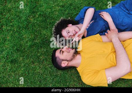 Junge Frau mit Freund auf Gras im Park liegen Stockfoto