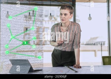 Eine Frau, die in der Nähe des Schreibtisches im Büro wegschaut Stockfoto