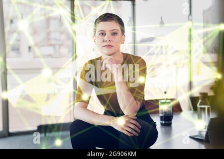 Eine Frau, die im Büro auf dem Schreibtisch sitzt und von globalen Kommunikationsdaten umgeben ist Stockfoto