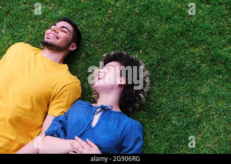 Glückliches junges Paar, das auf Gras im Park liegt Stockfoto