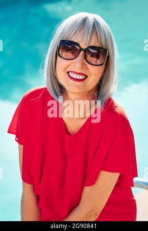 Lächelnde, reife Frau, die an sonnigen Tagen eine Sonnenbrille trägt Stockfoto