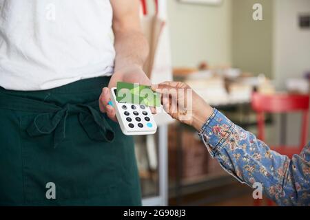 Frau mit Kreditkarte für kontaktlose Zahlung im Café Stockfoto