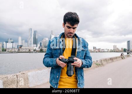 Junger Mann, der auf der Promenade steht und die Kamera überprüft Stockfoto