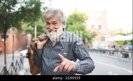 Glücklicher weißer bärtiger reifer Mann, der beim Tragen des Gepäcks gestikulierte Stockfoto