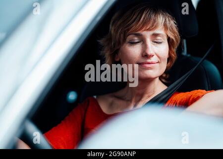 Geschäftsfrau sitzt mit geschlossenen Augen im Auto Stockfoto