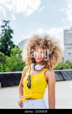 Lächelnd schöne junge Afro-Frau, die mit der Hand auf der Hüfte steht Stockfoto