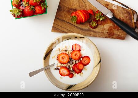 Studioaufnahme einer Schüssel Müsli mit Joghurt und frischen Erdbeeren Stockfoto