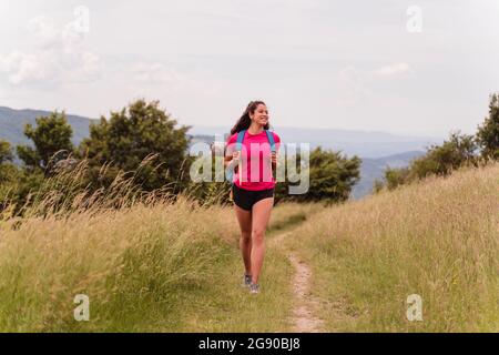 Lächelnde Wandererin schaut weg, während sie durch die Wiese geht Stockfoto